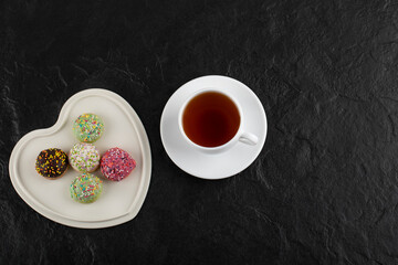 Obraz na płótnie Canvas A cup of a hot tea with sweet doughnuts on a white plate