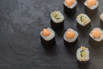 Rolls on a stone platter. Roll with cucumber, cheese sprinkled with sesame seeds. view from 45 degrees