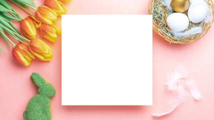 Easter card. Golden, white colour egg in basket with spring tulips, feathers on pastel pink background in Happy Easter decoration. Flat lay, top view with copy space.