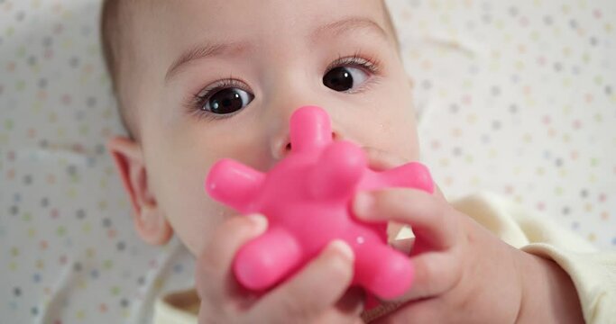 infant, childhood concept - close-up of smiling happy Baby plays with a teether. Teeth cutting. First teeth. Joy toothless 7 months baby bite, gnaws teether toy. slow motion