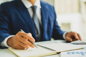 An Asian male finance worker or accountant is reviewing the investment results. To report at the meeting, audit ideas And investment results