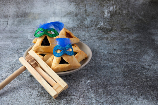 Purim celebration concept with hamantashen cookies, Purim mask and toy noisemaker on grey background