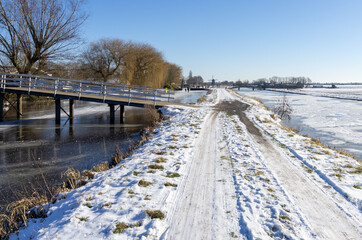 frozen and snowy Dutch landscape with clear blue sky. frozen water in canal. copy space. people in...