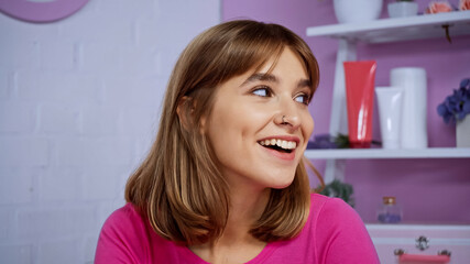 happy young woman with piercing smiling while looking away at home
