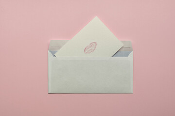 Handmade postcard with mark of lips from envelope on pink background