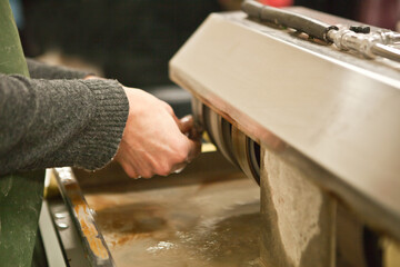 worker polishing boulder precious stone. worker hands, no face, unrecognizable person. worker cutting a stone