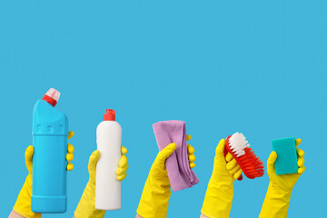 Hands in rubber yellow gloves with accessories and cleaning products with copy space