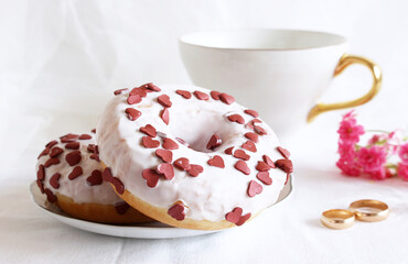 Styled stock photo. Donuts, two golden rings, and a cup of coffee on a white table. Retro style.Concept of breakfast. Food detail. Close up. Pastel color.