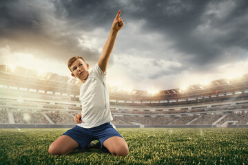 Fototapeta na wymiar Junior football or soccer player at stadium in flashlight. Young male sportive model training. Moment of win celebrating. Concept of sport, competition, winning, action, motion, overcoming.