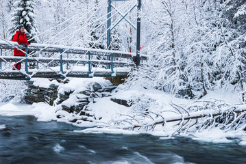 Woman standing on bridge in snowcovered landscape