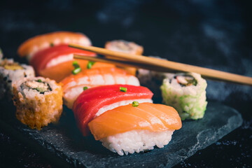 sushi set served on black stone slate on dark background selective focus copy space