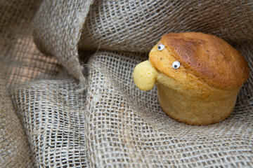 Side view of a funny character made of a homemade muffin on a burlap cloth.
