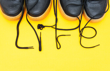 Crop view of two pairs of similar sneakers with the word LIFE made of the laces on a yellow...