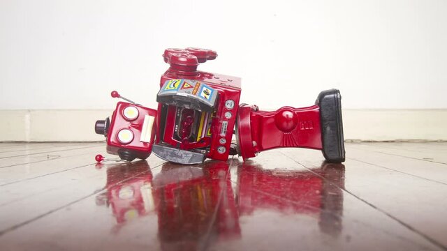A retro red robot is broken on an old wooden floor 
