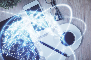 Double exposure of business theme hologram over desktop with phone. Top view. Mobile international trade connection concept.
