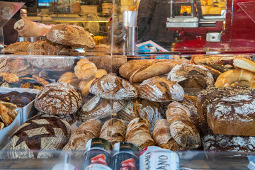 Freshly baked sourdough bread loaves for sale in a street market. Different kinds of artisan bread loaves displayed behind a glass window for shoppers. Market bakery at Naschmarkt, Vienna