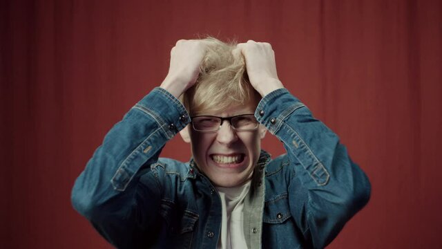 Student nervous man tearing his hair, guy having much problems, cannot solve them. angry male with hands on his head looking at the camera, he cannot believe in news