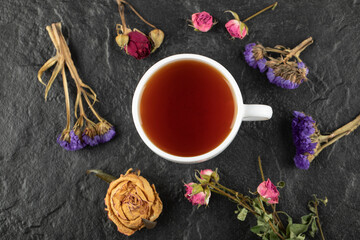 A cup of tea with dried flowers on a black background
