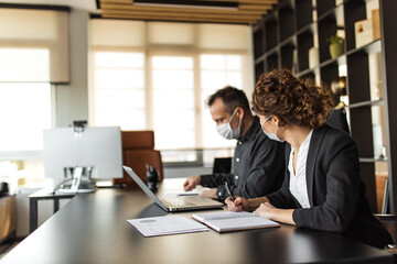 Man using laptop, woman writing some documents.