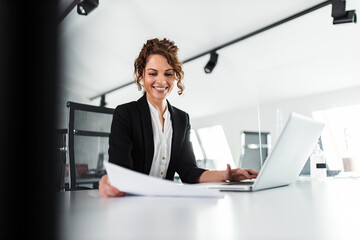 Portrait of a happy businesswoman looking at paper document and smiling.