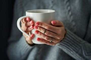 Cozy home. Female hands holding hot cup of coffee or tea.
