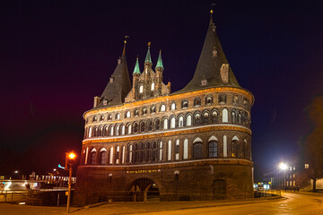 Obraz premium Holstentor in Lübeck angestrahlt bei Nacht