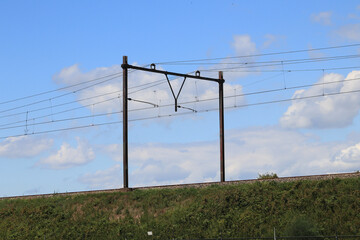 Embankment with catenary, blue sky in the background
