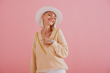 Happy smiling woman wearing trendy yellow v-neck sweater, white hat, elegant wrist watch, posing on...