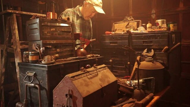 Camera dollies in and jibs up to old man working in garage.