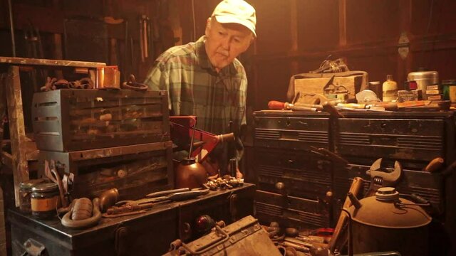 Camera dollies in to elderly man working at workbench.