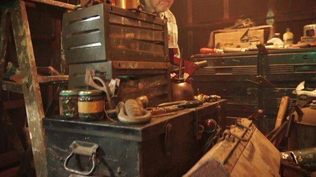 Camera trucks in and jibs up on old man at workbench.