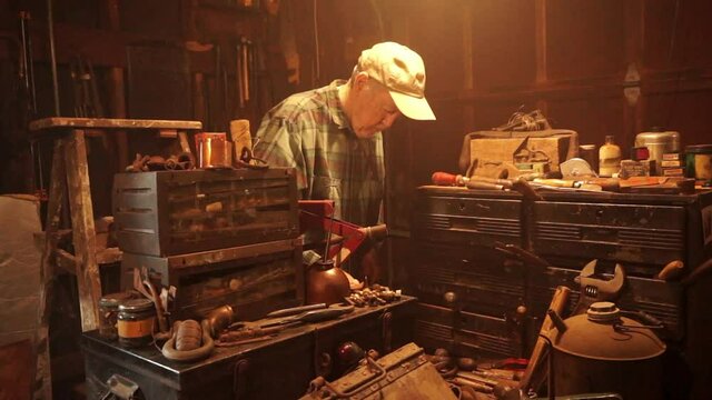 Camera trucks in to elderly man working in workshop.