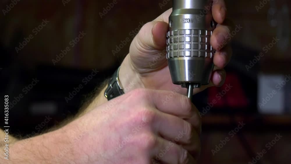Aufkleber installing a silver drill bit into a mill chuck by rotating it clock and anti clock wise in a drilli