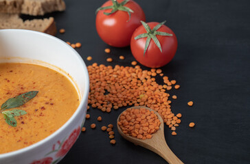 A white bowl of lentil soup with uncooked lentil beans