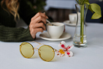 A beautiful girl is drinking coffee in a cafe, glasses are on the table