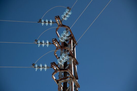 metal electricity pole with glass insulator and clear blue sky close up