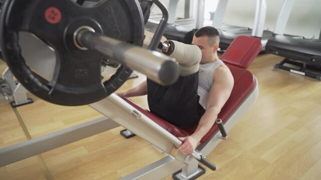 Disabled Athletic With leg prothesis does heavy workout for his legs at the gym