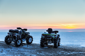 Obraz premium two ATVs at sunset over the frozen north sea