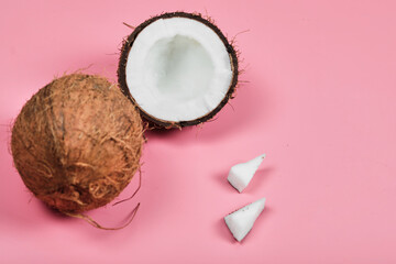 Whole coconut and half piece of coconut on pink background