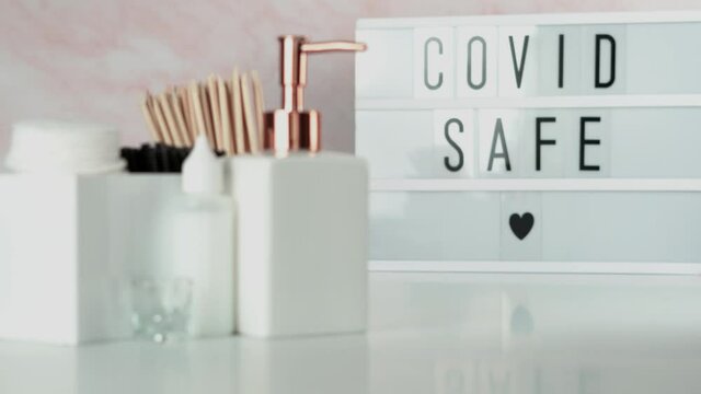 Covid 19 Safe sign in a beauty salon. Salon compliance with Corona Virus guidelines for health and safety of clients and customers. Real time motion footage, focus change in light modern beauty salon 