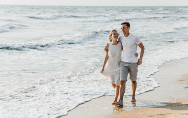 beautiful loving couple walks on the seashore. happy young couple spend time on the beach. honeymoon newlyweds. guy with girl at dawn of the day. couple on vacation. summer rest. couple hugging