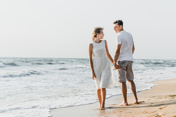 beautiful loving couple walks on the seashore. happy young couple spend time on the beach. honeymoon newlyweds. guy with girl at dawn of the day. couple on vacation. summer rest. couple hugging