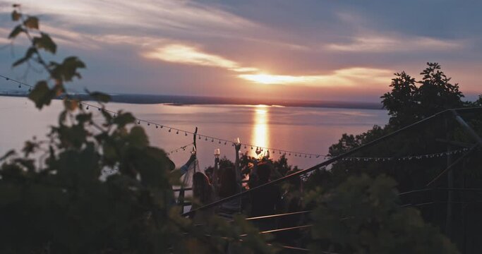 Group of friends toasting with wine at sunset in front of the sea