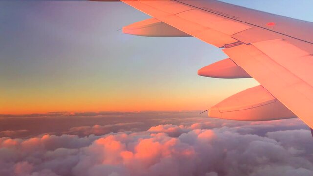 Airplane flight. Wing of an airplane flying above the clouds with sunset sky. View from the window of the plane. Airplane, Aircraft. Traveling by air. 4K UHD video. 