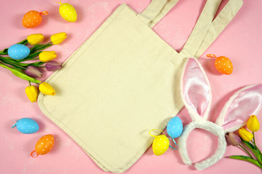 Easter product mockup with bunny ears and easter eggs on pink background flatlay. Natural organic eco cotton tote bag mock up with negative copy space for your text or design here.