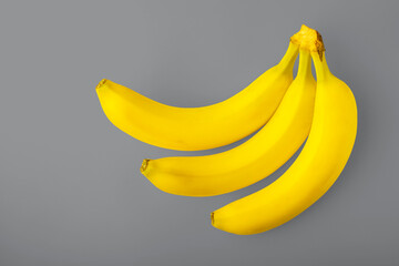 Drei gelbe Bananen auf grauem Hintergrund. Der Farbtrend 2021 ist Yellow, Ultimate Grey. Gesundes Ernährungskonzept © art_rich