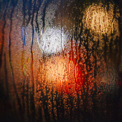 Multicolored evening lights and drops on glass