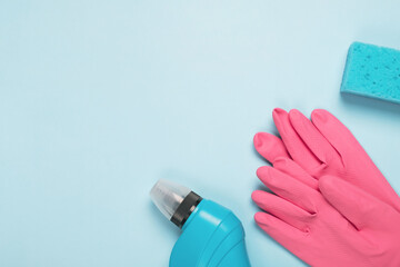 Cleaning supplies, sponge, rubber protective glove on light blue background. Spring or regular cleanup concept. Top view, flat lay, copy space