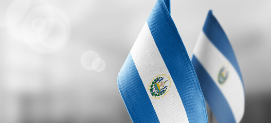 Small national flags of the Salvador on a light blurry background - obrazy, fototapety, plakaty