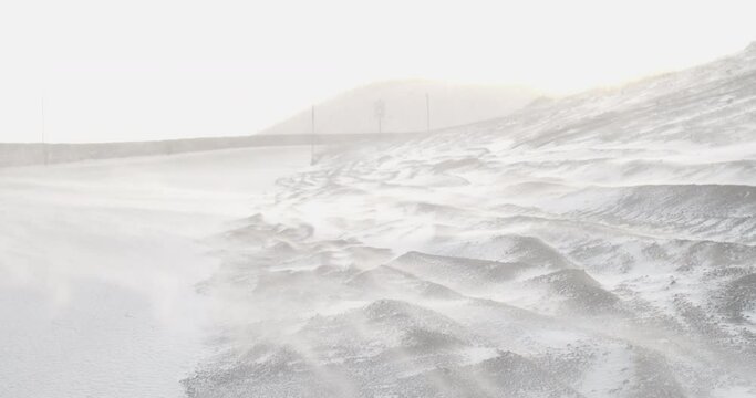 White snow blowing over rocks covered with ice and snow at the vulcano Etna at Sicilia Italy on a windy day. Close-up shot